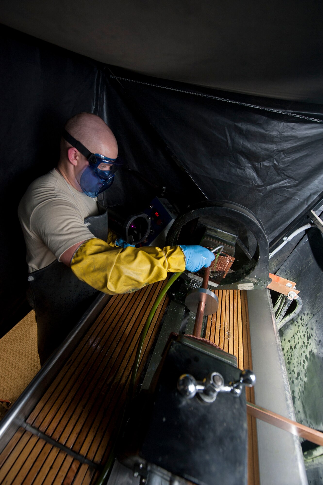 Senior Airman Kyle Abendroth, 5th Maintenance Squadron non-destructive inspection journeyman, uses a magnetic particle machine at Minot Air Force Base, N.D., Aug. 26, 2015. The magnetic particle machine magnetizes ferromagnetic metal parts, which are composed mostly of iron. Once magnetized any surface or subsurface cracks are made visible by a buildup of particles from the oil bath which glow under black light. (U.S. Air Force photo/Senior Airman Stephanie Morris)