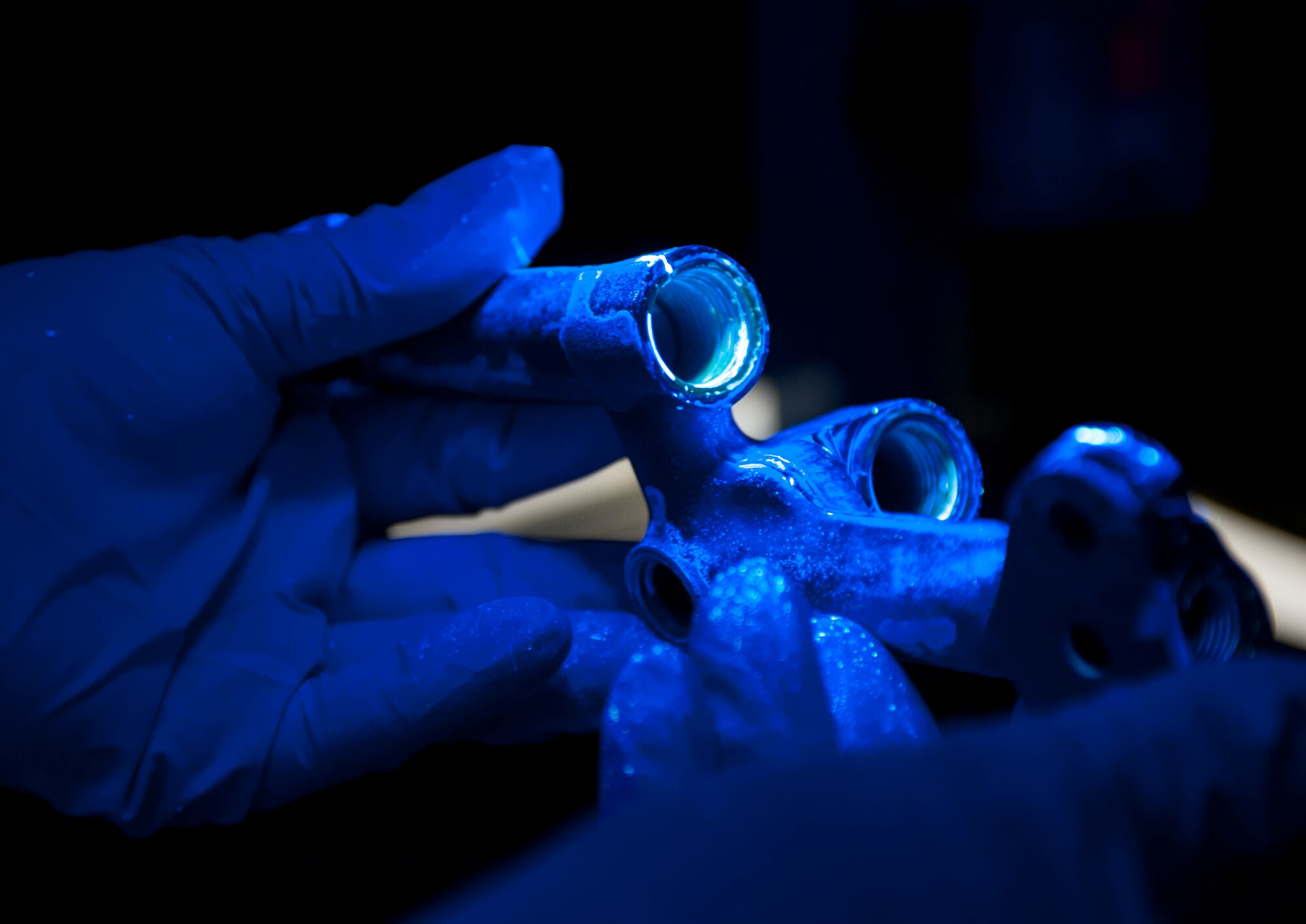 A metal part held under a black light in the non-destructive inspection lab at Minot Air Force Base, N.D., Aug. 26, 2015. NDI Airmen are able to use X-rays, chemical developers, black lights and magnetism to detect deficiencies in aircraft and ground equipment parts without having to further damage them. (U.S. Air Force photo/Senior Airman Stephanie Morris)
