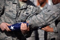 U.S. Air Force Airmen from the RAF Mildenhall Honor Guard fold the flag during a monthly retreat ceremony Aug. 28, 2015, on RAF Mildenhall, England. The U.S. flag and Royal Air Force ensign are folded to signify the end of the duty day. (U.S. Air Force photo by Senior Airman Christine Halan/Released)