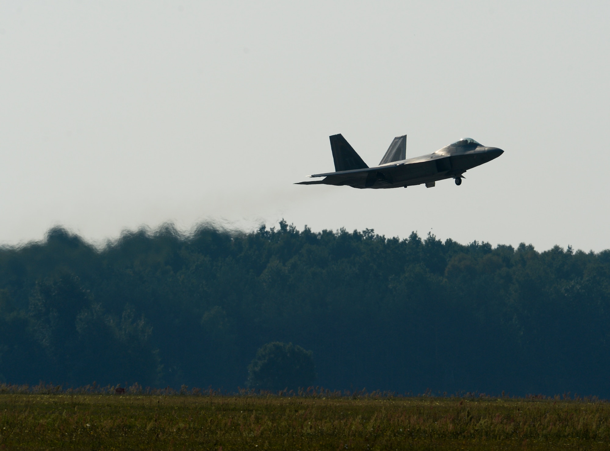 A U.S. Air Force F-22 Raptor flies over the flightline at Lask Air Base, Poland, Aug. 31, 2015. The aircraft will conduct air training with other Europe-based aircraft and will also forward deploy from Germany to maximize training opportunities while demonstrating the U.S. commitment to NATO allies and the security of Europe. The F-22s are deployed from the 95th Fighter Squadron at Tyndall Air Force Base, Florida. (U.S. Air Force photo by Staff Sgt. Joe W. McFadden/Released)