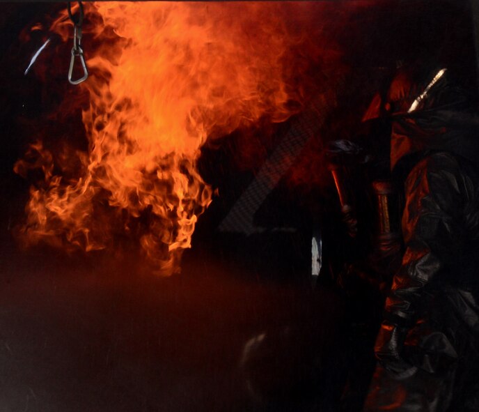Staff Sgt. Michael White, 51st Civil Engineer Squadron crew chief, stands aside while members of the Songtan fire department put out a fire inside a training aircraft Aug 26, 2015, at Osan Air Base, Republic of Korea. After the initial fire is out, the firefighters continue to spray the burn site until all the hot spots are cool to prevent flare-ups. (U. S. Air Force photo by Staff Sgt. Benjamin Sutton)  