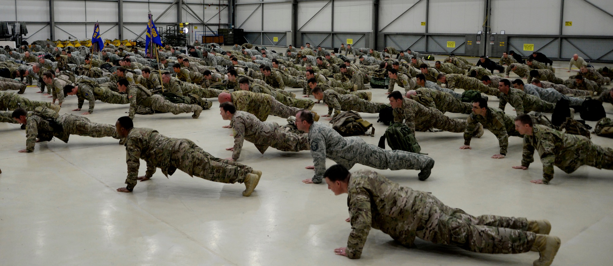 U.S. Air Force Airmen perform memorial push-ups after participating in a ruck march in honor of the “Year of the Air Commando” Nov. 30, 2015, on RAF Mildenhall, England. The theme of the event was “Honoring Our Past Air Commandos” and photographs of those who perished in combat since Sept. 11, where displayed throughout the hangar as a memorial. (U.S. Air Force photo by Senior Airman Victoria H. Taylor/Released)