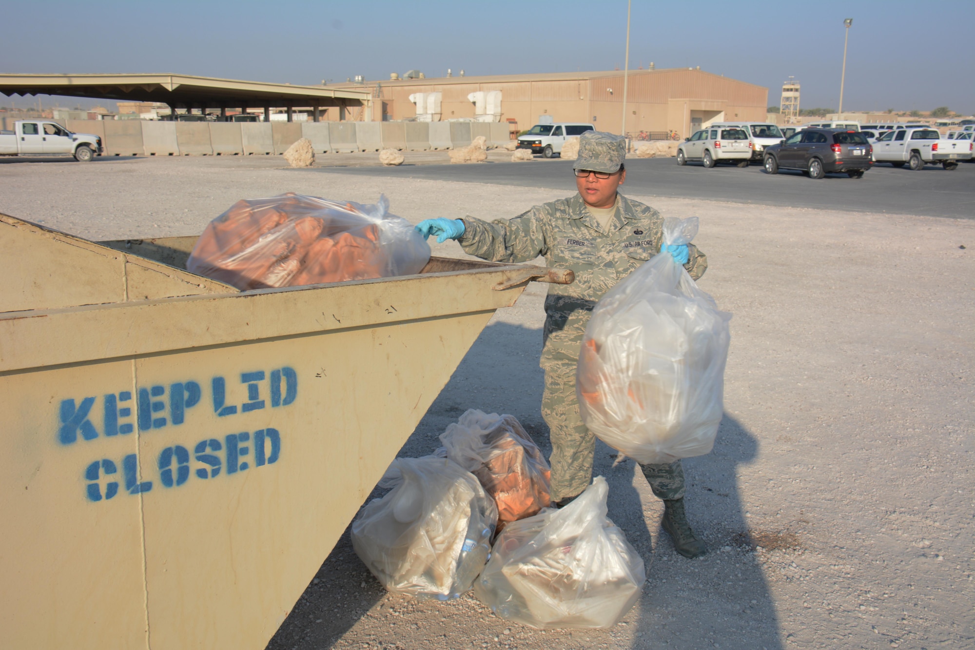 Tech. Sgt. Jocelyn Ferber, U.S. Air Force’s Central Command's Protocol non-commissioned officer in charge, throws one of five bags of trash into a dumpster during an Operation Community clean-up event at Al Udeid Air Base, Qatar Dec. 1. Ferber, a native of Joint Base Lewis-McChord, Washington, said she enjoyed helping clean up the base. More than 70 volunteers took part in the event collecting 130 bags of trash in one hour. (U.S. Air Force photo by Tech. Sgt. James Hodgman/Released)