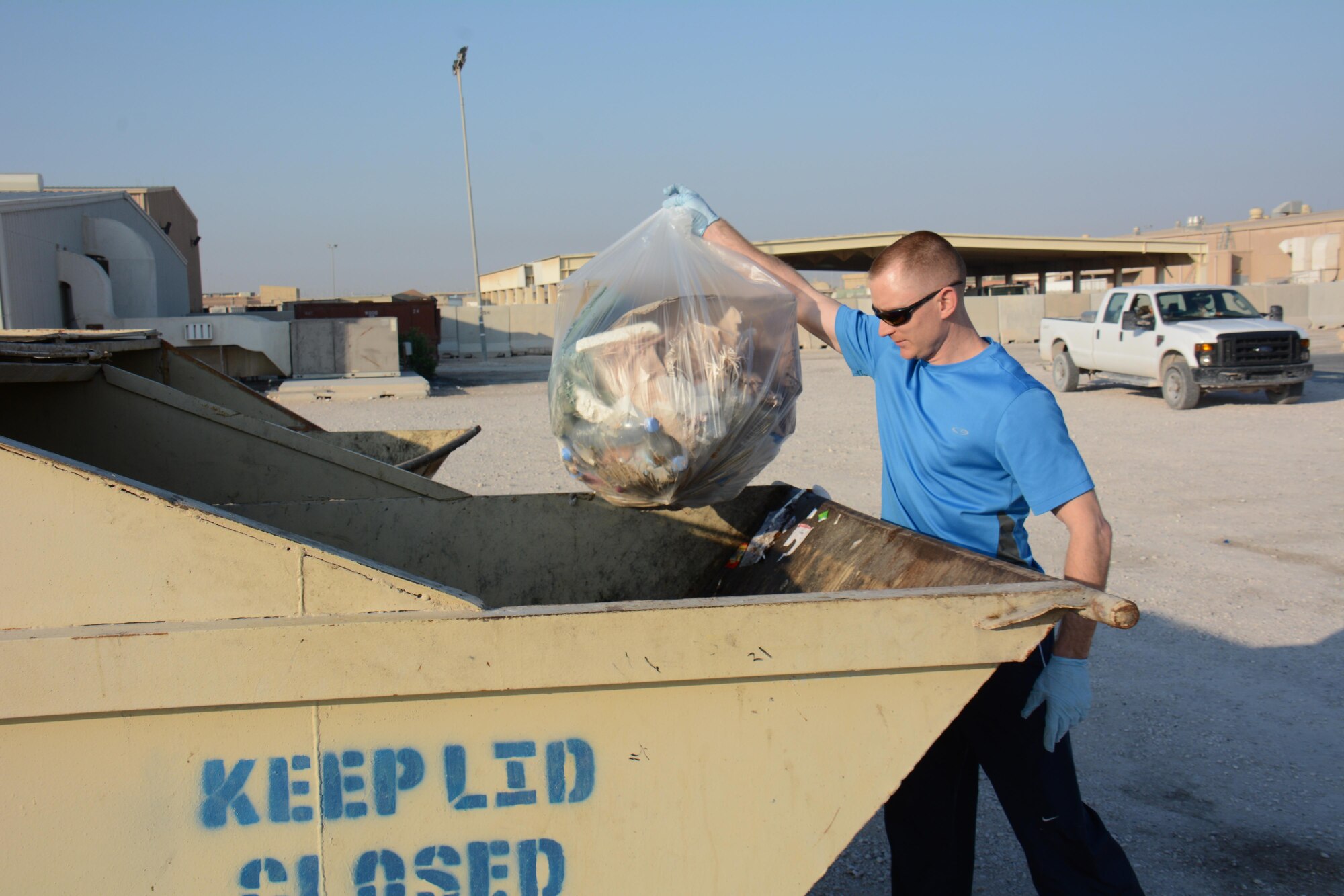 Tech. Sgt. David Stai, 379th Expeditionary Aircraft Maintenance Squadron section chief from Portland, Oregon, throws a trash bag into a dumpster during an Operation Community clean-up event at Al Udeid Air Base, Qatar Dec. 1. More than 70 volunteers took part in the event collecting 130 bags of trash in one hour. (U.S. Air Force photo by Tech. Sgt. James Hodgman/Released)