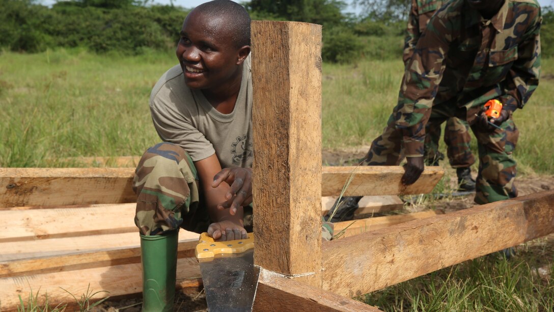 A Uganda People’s Defense Force soldier saws the top of a post in preparation to finish the flooring during a civil engineering exercise at Camp Singo, Nov. 16, 2015. The exercise helps the partner nations fortify their civil engineering skills while strengthening the bond between the two.