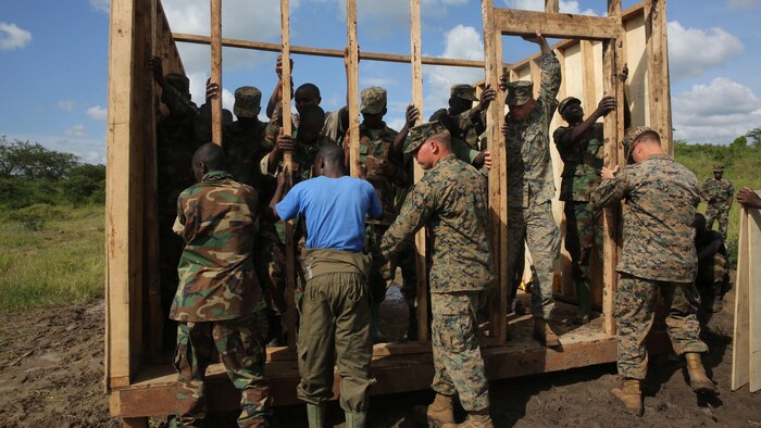 U.S. Marine combat engineers with Special-Purpose Marine Air-Ground Task Force Crisis Response-Africa, assist Uganda People’s Defense Force soldiers nail in one of the wall frames during a civil engineering exercise at Camp Singo, Nov. 19, 2015. The exercise helps the partner nations fortify their civil engineering skills while strengthening the bond between the two.