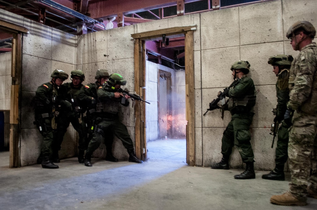 An explosive door-breaching charge detonates during a live-fire exercise as members of the Colombian Compañía Jungla Antinarcóticos assault a doorway inside an Eglin Air Force base shoot house on November 20, 2015.  