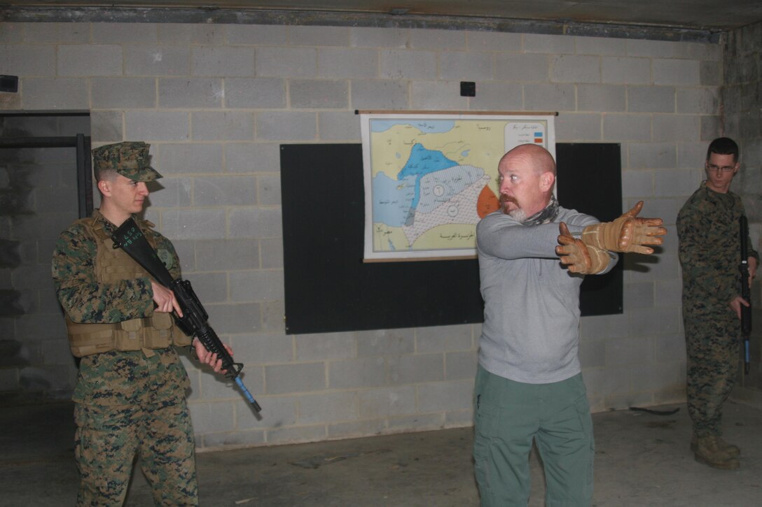 Matt Koziol, a contracted trainer with Homeland Security Systems, Inc., instructs two Marines from the Quantico Security Augmentation Force on how to effectively clear a room of an active shooter.
