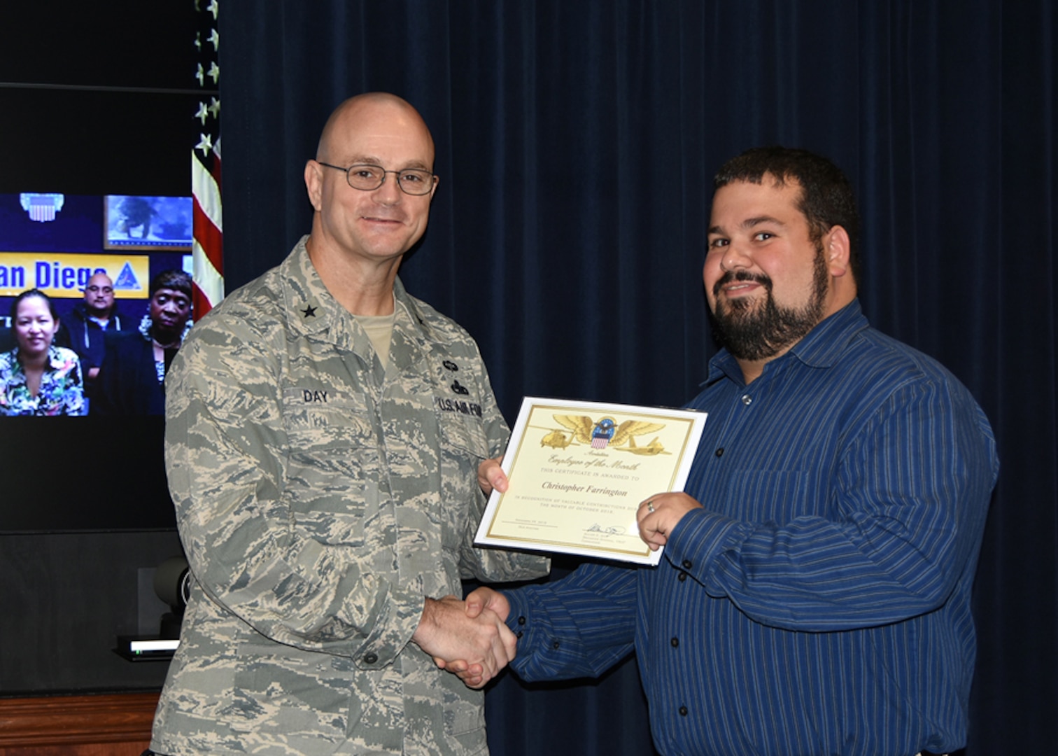 Defense Logistics Agency Aviation Commander Air Force Brig. Gen. Allan Day congratulates Christopher Farrington on being selected as DLA Aviation’s October Employee of the Month during a ceremony Nov. 25, 2015. Farrington serves as a project manager for the Industrial Plant Equipment Services Division of DLA Aviation’s Engineering Directorate in Richmond, Virginia. 