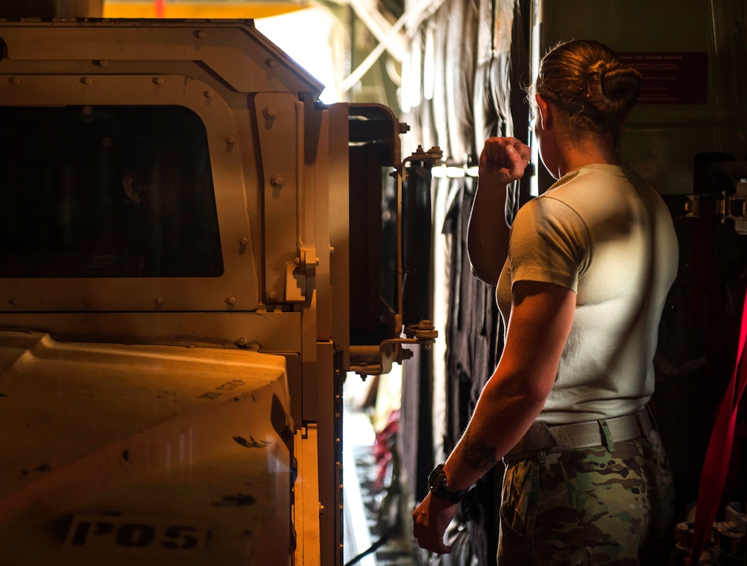 U.S. Air Force Staff Sgt. Whitney Woolverson directs an armored Humvee into a C-130J Super Hercules aircraft on Camp Lemonnier, Djibouti, Nov. 24, 2015. Woolverson is a loadmaster assigned to the 75th Expeditionary Airlift Squadron. U.S. Air Force photo by Senior Airman Peter Thompson