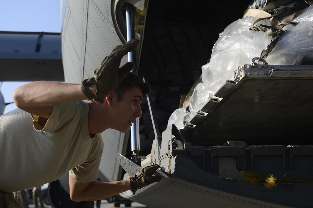 U.S. Air Force Senior Airman Zachary McGhee instructs a forklift operator to lower cargo onto a C-130J Super Hercules aircraft on Camp Lemonnier, Djibouti, Nov. 24, 2015. McGhee is a loadmaster assigned to the 75th Expeditionary Airlift Squadron. U.S. Air Force photo by Senior Airman Peter Thompson