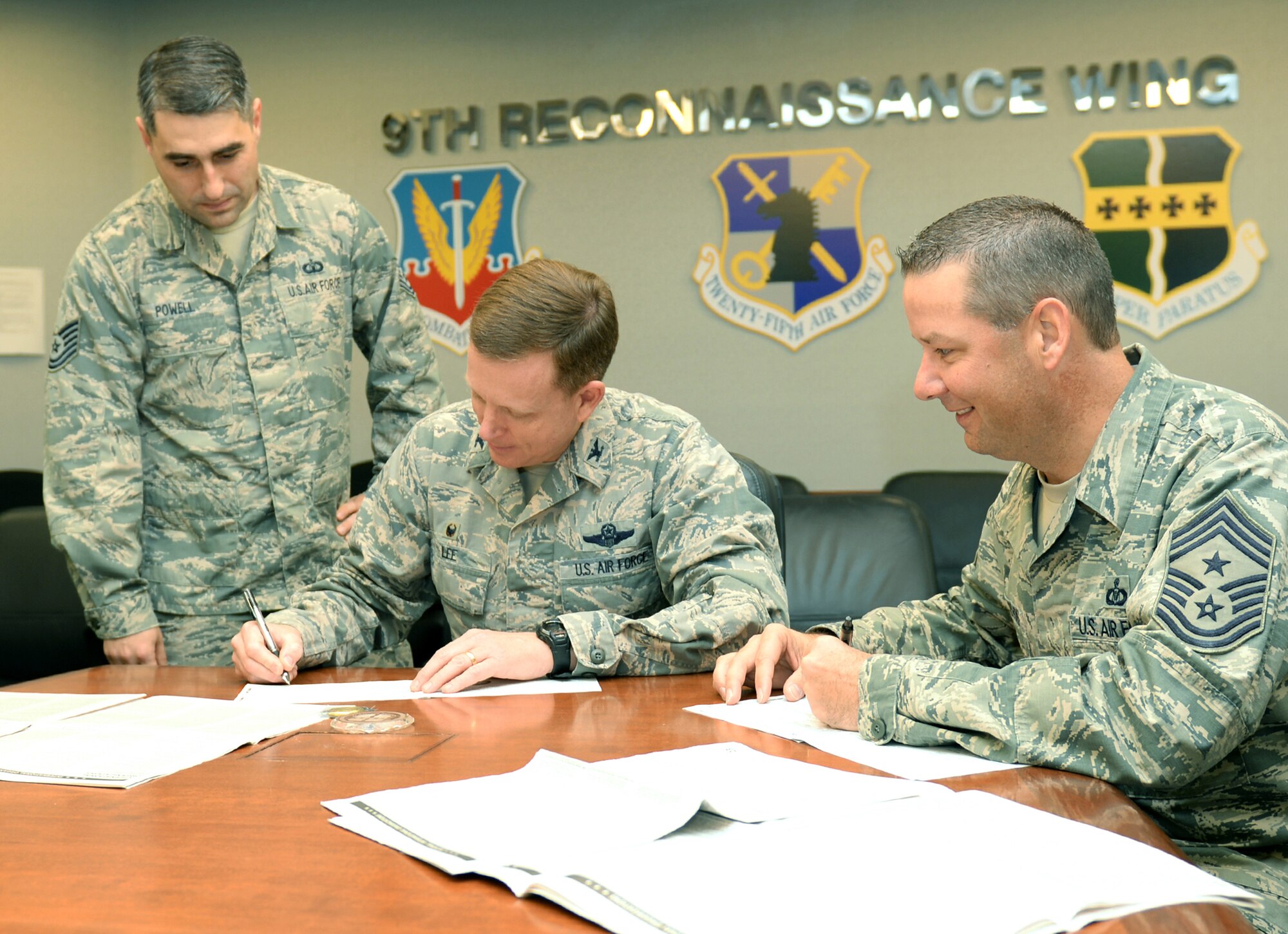 Col. Douglas Lee (center), 9th Reconnaissance Wing commander, and Command Chief Master Sgt. Randy Kwiatkowski (right), 9 RW command chief, sign their Combined Federal Campaign donations Dec. 1, 2015. The CFC is the only authorized solicitation of Federal employees in the workplace on behalf of charitable organizations. (U.S. Air Force photo by Robert Scott)