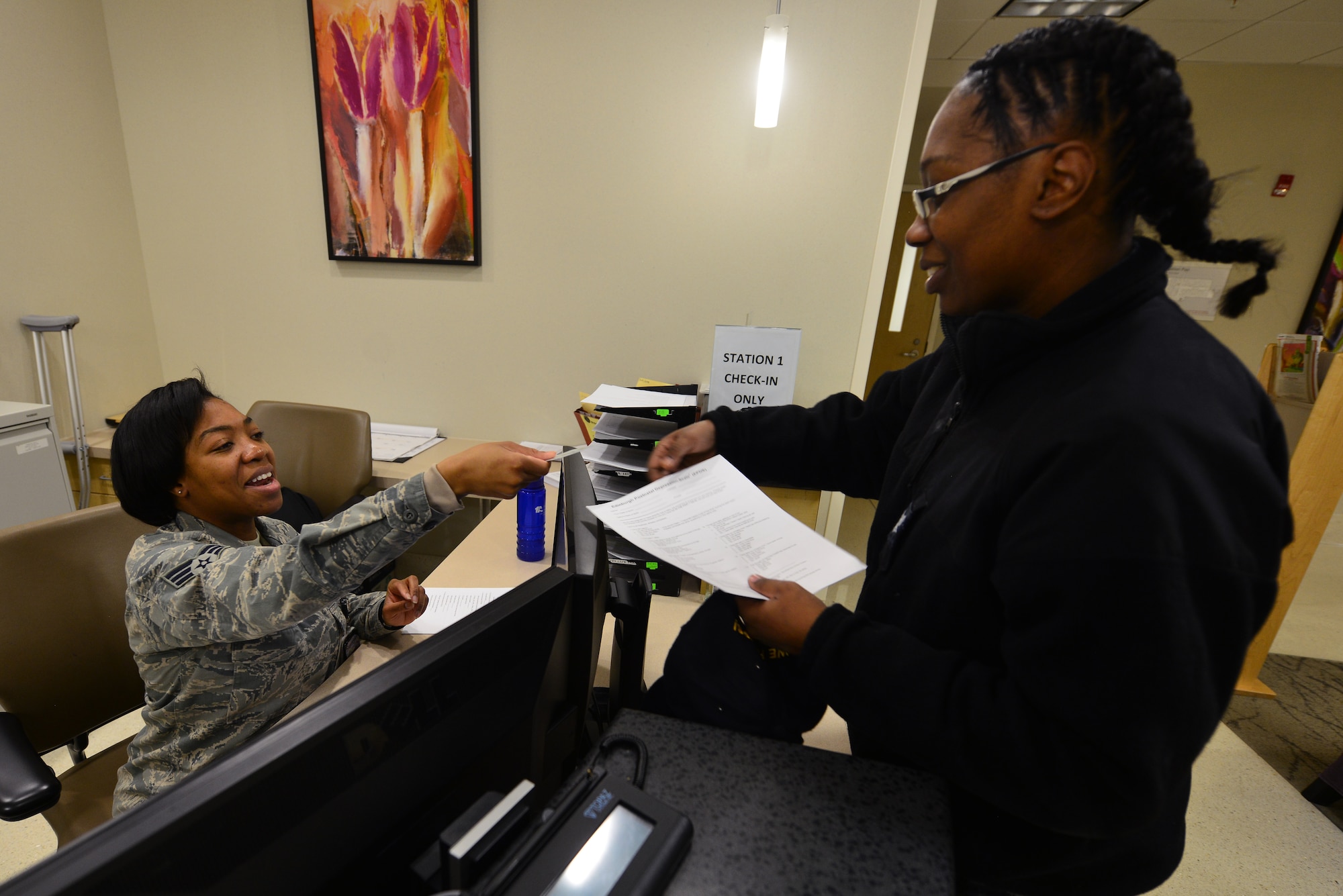 U.S. Air Force Senior Airman Raviro Mutuhme, an aerospace medical service technician assigned to the 633rd Medical Group, hands an ID card back to U.S. Navy Petty Officer 3rd Class Yasmine Debreaux, an electronics technician assigned to the Mid Atlantic Regional Maintenance Center, before a Women’s Health Clinic appointment at Langley Air Force Base, Va., Nov. 23, 2015. After receiving a positive pregnancy test, female Service members, spouses and daughters will visit the clinic for an overall health assessment including nutrition education for the mother-to-be. (U.S. Air Force photo by Senior Airman Aubrey White)