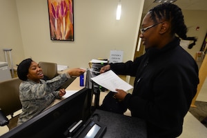 U.S. Air Force Senior Airman Raviro Mutuhme, an aerospace medical service technician assigned to the 633rd Medical Group, hands an ID card back to U.S. Navy Petty Officer 3rd Class Yasmine Debreaux, an electronics technician assigned to the Mid Atlantic Regional Maintenance Center, before a Women’s Health Clinic appointment at Langley Air Force Base, Va., Nov. 23, 2015. After receiving a positive pregnancy test, female Service members, spouses and daughters will visit the clinic for an overall health assessment including nutrition education for the mother-to-be. (U.S. Air Force photo by Senior Airman Aubrey White)