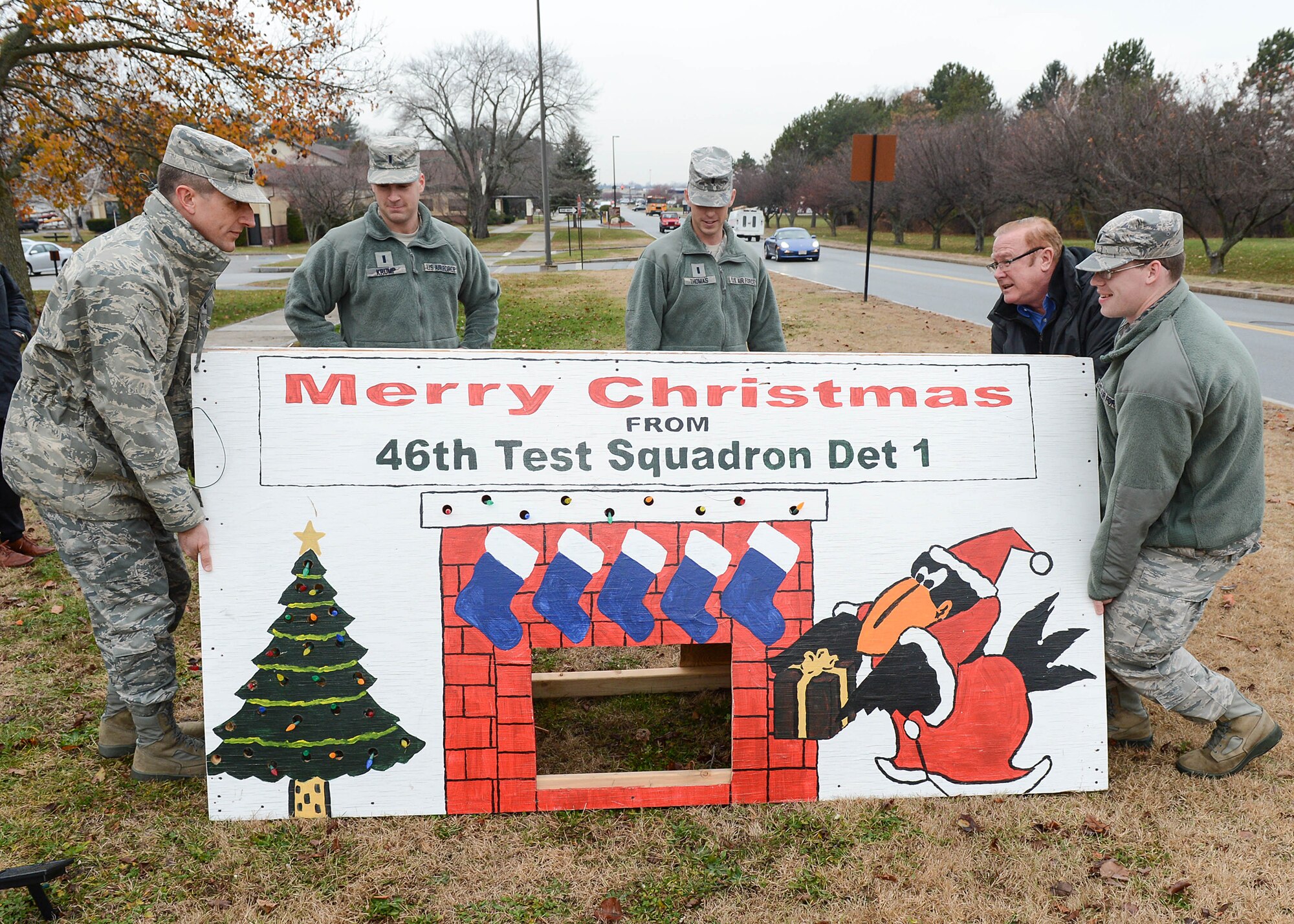 Members of the 46th Test Squadron, Detachment 1, move a large squadron Christmas card outside of Building 1521 to display throughout the month. Moving the display into place is from left-to-right, Lt. Col. Bradley D. Rennich, 46 TS commander, and Test Engineers, 1st Lt. Brian Krump, 1st Lt. Wesley Thomas, Joe Foley and 1st Lt. John Covert. (U.S. Air Force photo by Jerry Saslav)