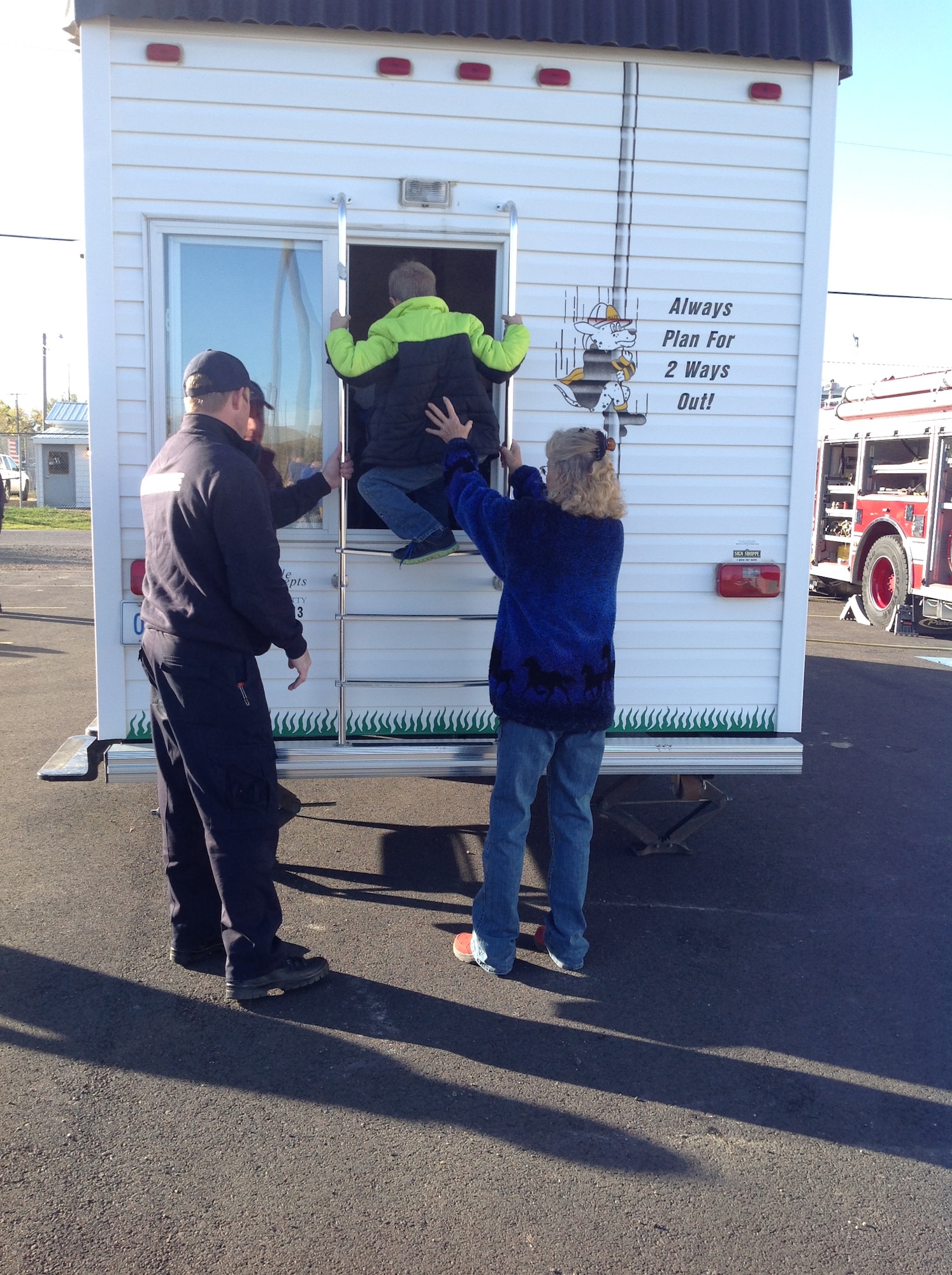 A trainer is helping a student practice exiting through a window properly in case of a fire. The fire prevention trailer was used by members of the 120th Airlift Wing’s Fire Department during an educational visit to local public schools in Cascade County, Mont. (Photo by Terry Rutherford/Released)