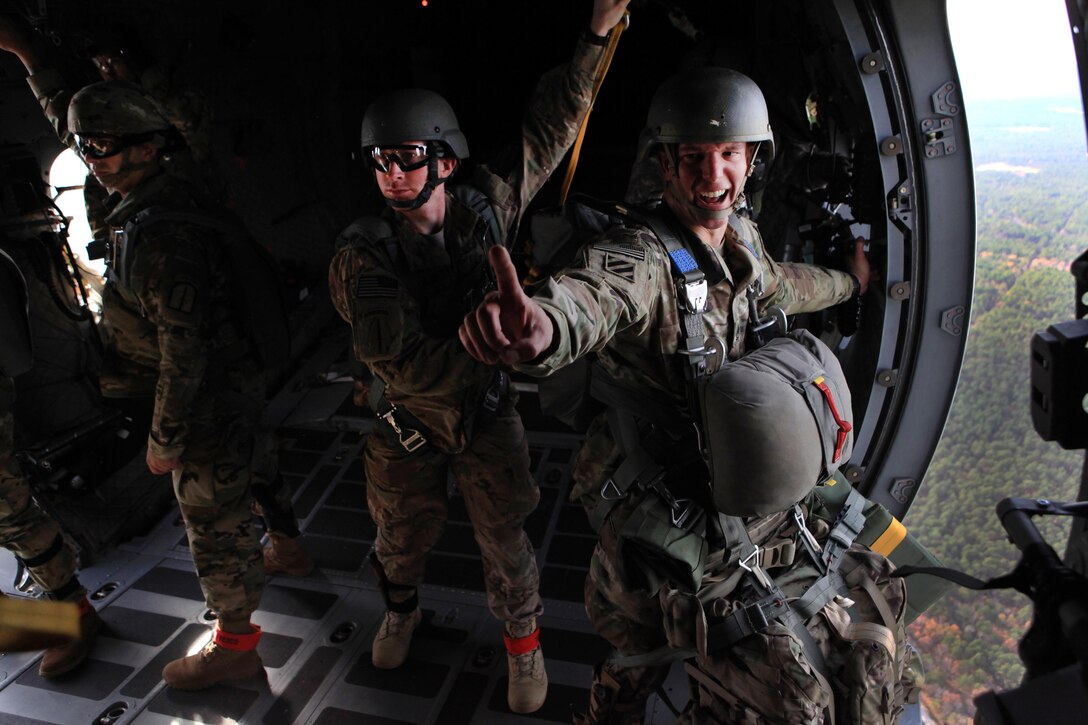 An Army jumpmaster gives a one-minute time warning from the troop door of a C-27 Spartan aircraft during airborne operations over the St. Mere-Eglise drop zone on Fort Bragg, N.C., Nov. 25, 2015. U.S. Army photo by Sgt. 1st Class Sean A. Foley