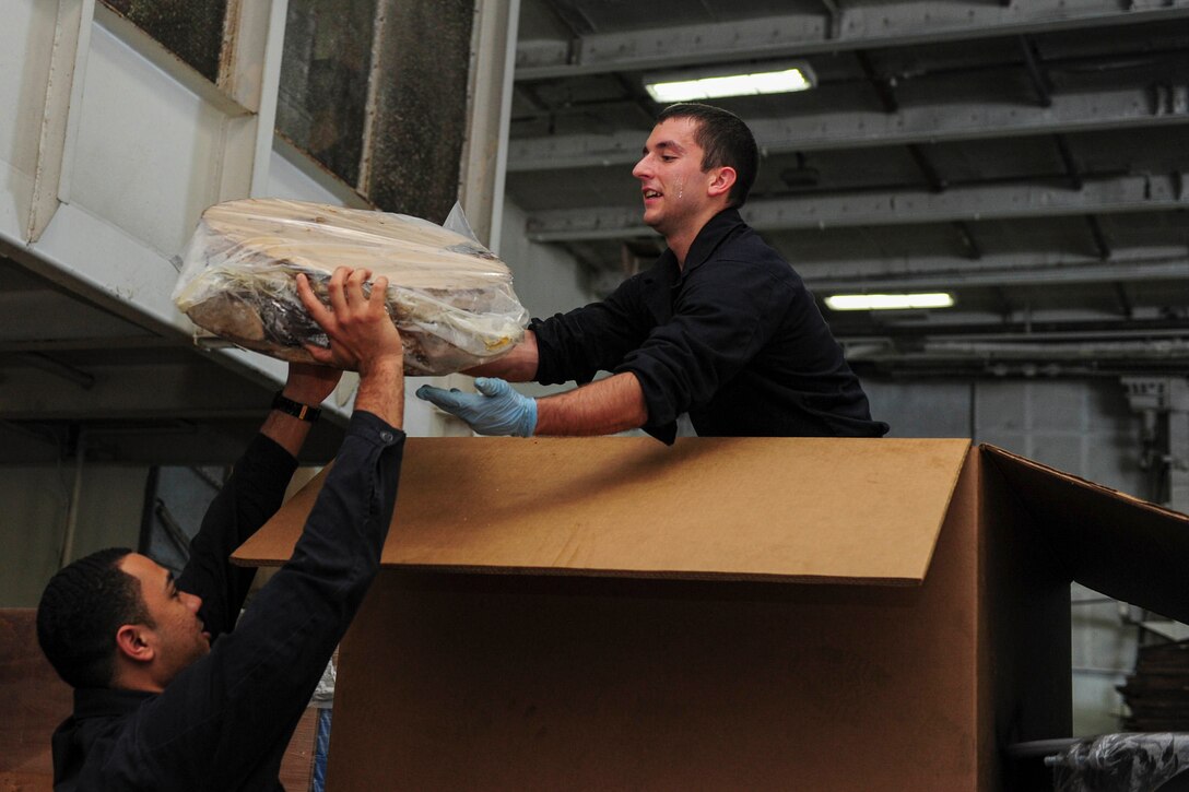 U.S. Navy Seaman Montana Davis (left) and Airman Apprentice Chris Dukette load recyclable plastic discs into a tri-wall box for stowage in the hangar bay of the aircraft carrier USS Dwight D. Eisenhower in the Atlantic Ocean, Nov. 25, 2015. U.S. Navy photo by Petty Officer 3rd Class Taylor L. Jackson