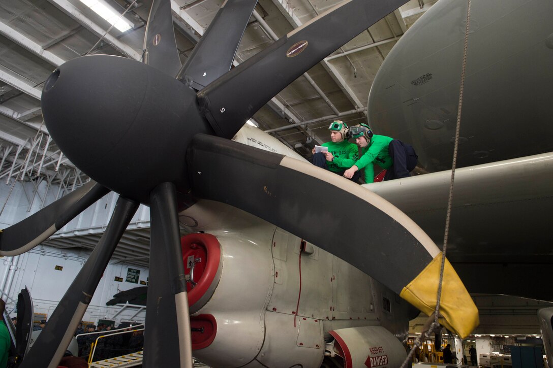Navy Petty Officer 1st Class Christopher Marsh, left, and Petty Officer 3rd Class Phillip Botts conduct a corrosion inspection on an E-2C Hawkeye in the hangar bay of the USS Dwight D. Eisenhower in the Atlantic Ocean, Nov. 25, 2015. Marsh is an aviation structural mechanic and Botts is an aviation electronics technician. The aircraft is assigned to Airborne Early Warning Squadron 123. U.S. Navy photo by Petty Officer Seaman Anderson W. Branch