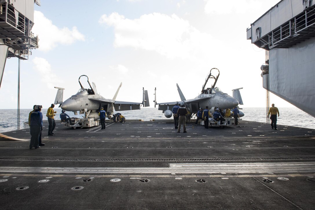 U.S. sailors prepare to transport two F/A-18E Super Hornets from the hangar bay to the flight deck of the aircraft carrier USS Dwight D. Eisenhower in the Atlantic Ocean, Nov. 27, 2015. The sailors are assigned to the Fighting Swordsmen of Strike Fighter Squadron 32. U.S. Navy photo by Seaman Anderson W. Branch