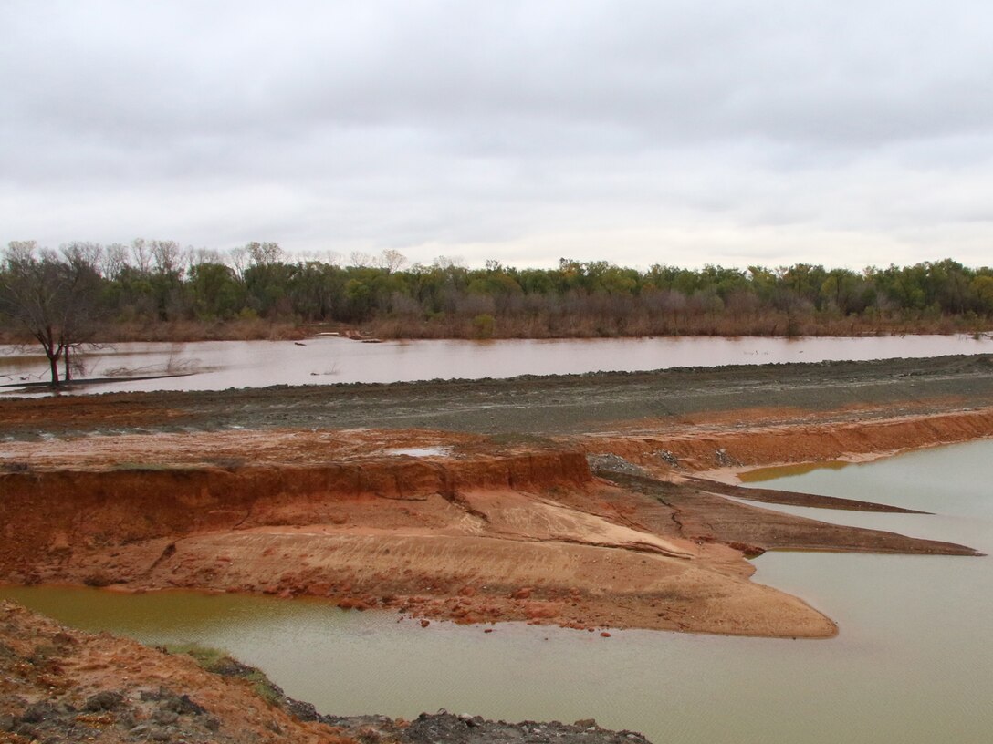 The temporary cofferdam at the Cumberland Levee repair site has been reinforced with a 36” windrow to keep water from overtopping the structure after several days of rain once again brought water levels out of the banks of the Washita River near the construction site Nov. 30, 2015. The dam was built for events such as this in order to keep the site free of excess water during high-water events. The Cumberland Levee repair site is in Phase I of a repair project by the Tulsa District, U.S. Army Corps of Engineers, after breaching earlier in 2015 due to record amounts of rainfall. (Photo by Preston Chasteen/Released)