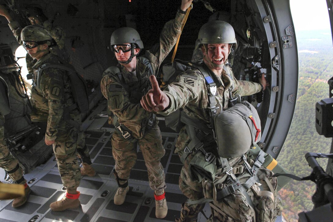 An Army jumpmaster gives a one-minute time warning from the troop door of a C-27 Spartan aircraft during airborne operations over the St. Mere-Eglise drop zone on Fort Bragg, N.C., Nov. 25, 2015. U.S. Army photo by Sgt. 1st Class Sean A. Foley