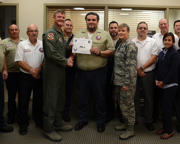 Cecilio Saenz, center, 47th Maintenance Directorate quality assurance inspector, poses with Col. Thomas Shank, left, 47th Flying Training Wing commander, and Chief Master Sgt. Teresa Clapper, 47th FTW command chief, after accepting the “XLer of the Week” award, here, Nov. 18, 2015. The XLer is a weekly award chosen by wing leadership and is presented to those who consistently make outstanding contributions to their unit and Laughlin. (U.S. Air Force photo by Airman 1st Class Brandon May)
