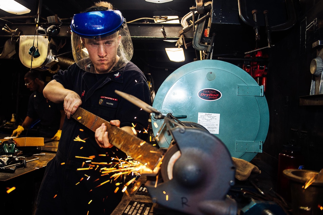 U.S. Navy Petty Officer 2nd Class Zachary Skates grinds a piece of metal aboard the amphibious assault ship USS Essex in the Pacific Ocean, Dec. 1, 2015. The Essex and its embarked 15th Marine Expeditionary Unit are operating in the U.S. 3rd Fleet area of operations. U.S. Navy photo by Petty Officer 2nd Class Liam Kennedy