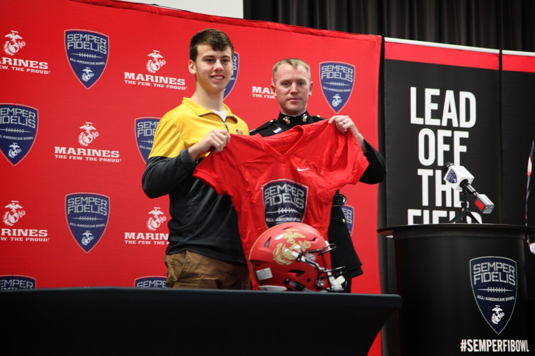 Capt. Ryan Kilkenny presents Tucker McCann his Semper Fidelis Bowl Game Jersey at a presentation at O'Fallon High School, O'Fallon, IL Dec. 2. Tucker, one of the top place kickers in the nation and University of Missouri commit, will play for the West Team during the 5th annual Semper Fidelis Bowl Game in Carson, CA. 