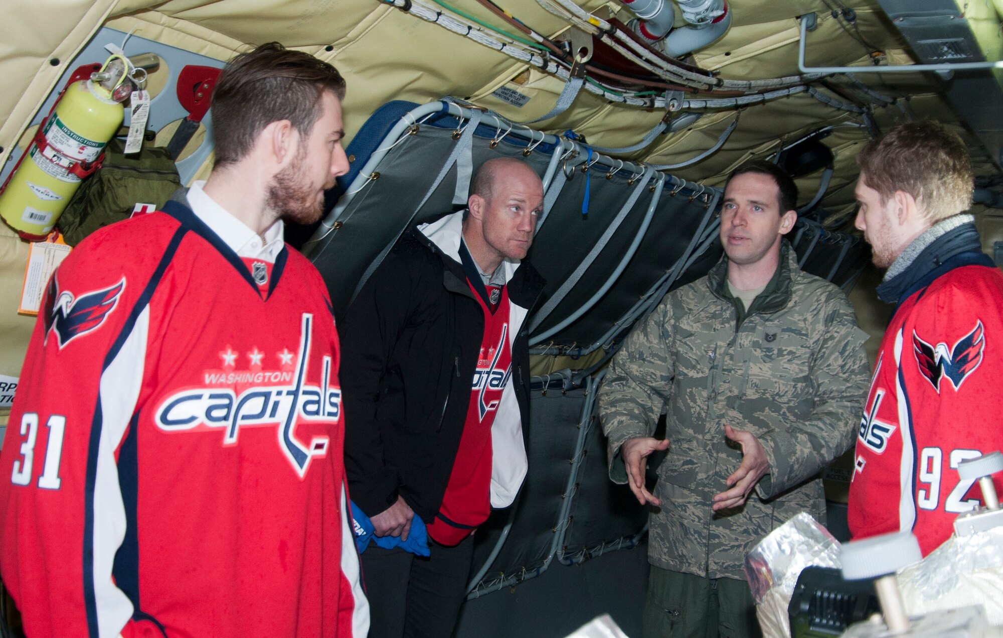 Technical Sgt. Matt Oberlin, 756th Air Refueling Squadron boom operator (right), explains the role and operations of a boom operator to a group of Washington Capitals players on board a 459th Air Refueling Wing KC-135R Stratotanker on Joint Base Andrews, Md., flight line Dec. 1, 2015. . The Capitals visited JBA to learn about the Air Force mission here. They observed special performances by the U.S. Air Force band Max Impact, Honor Guard, 11th Wing Explosive Ordnance Disposal, as well as static displays from the 1st Helicopter Squadron and 459 ARW, 113th Wing, Air National Guard. (U.S. Air Force photo by Staff. Sgt. Kat Justen)