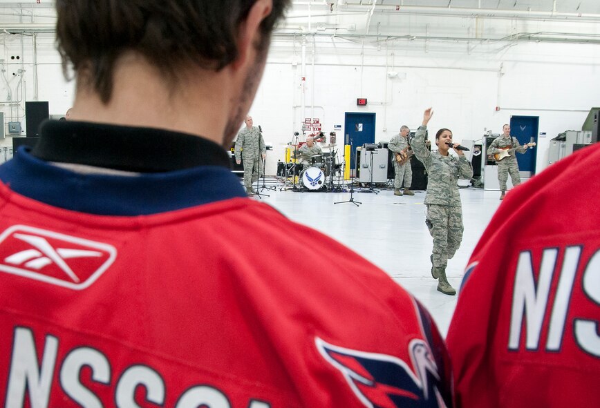 Players with the Washington Capitals watch the USAF Band Max Impact perform American Airman in the 459th Air Refueling Wing hangar on Joint Base Andrews, Md., Dec. 1, 2015. The Capitals visited JBA to learn about the Air Force mission. They observed special performances by the U.S. Air Force band Max Impact, Honor Guard, 11th Wing Explosive Ordnance Disposal, as well as static displays from the 459 ARW, 1st Helicopter Squadron and 113th Wing, Air National Guard. (U.S. Air Force photo by Staff. Sgt. Kat Justen)