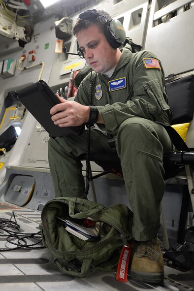 Senior Airman Taylor Beams, 3rd Airlift Squadron C-17A loadmaster, reads his iPad inside the cargo compartment of the aircraft during a training mission Nov. 23, 2015, from Dover Air Force Base, Del. The Air Force has moved away from heavy printed volumes of information for flight crews by issuing electronic flight books on iPads. (U.S. Air Force photo/Greg L. Davis)