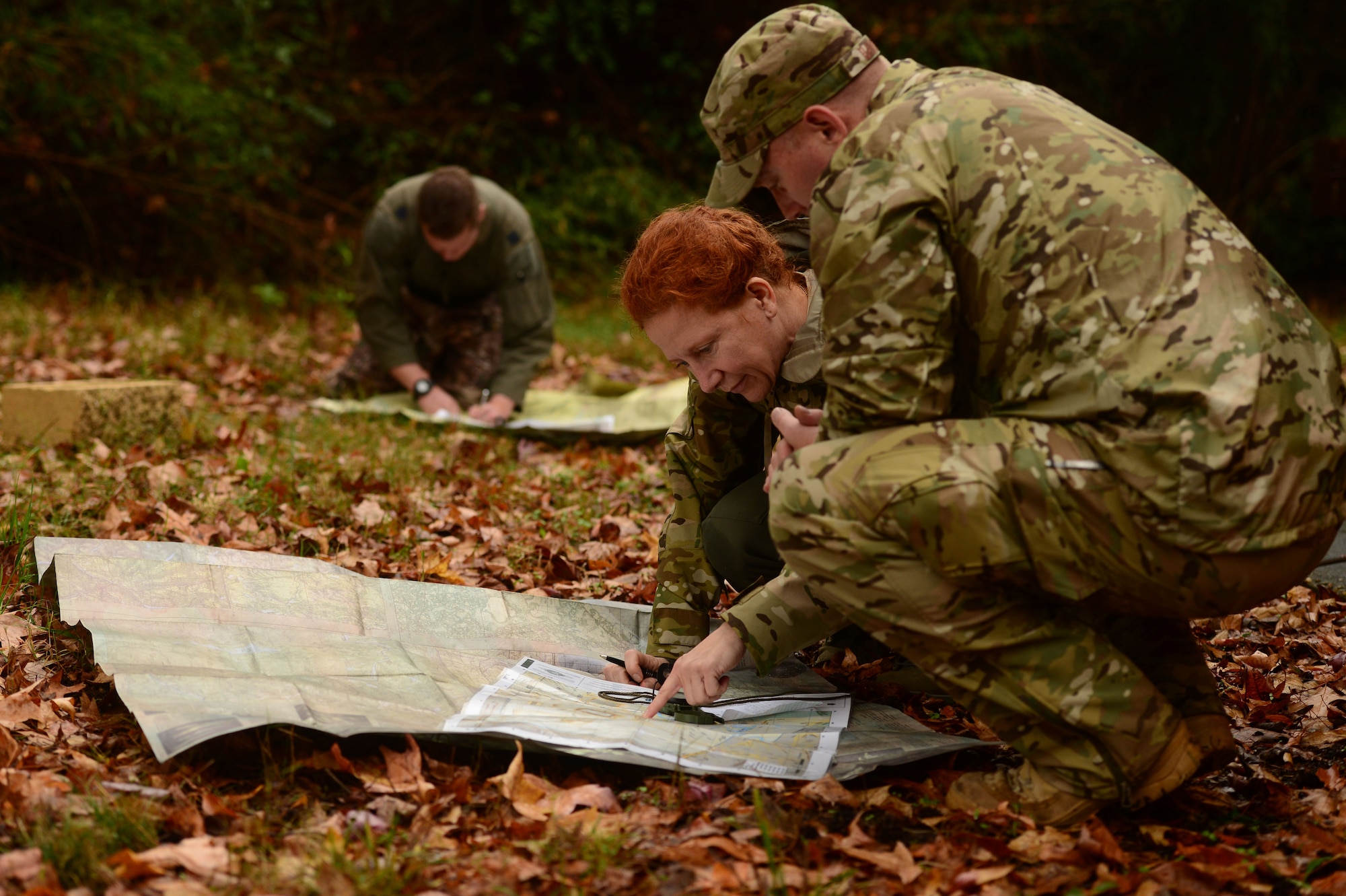U.S. Air Force Tech. Sgt. Sean Hanson, a survival, evasion, resistance and escape (SERE) specialist assigned to the 1st Operations Support Squadron, assists Col. Laura Brodhag, a chief flight surgeon assigned to the 633rd Medical Group, plan a course of direction through wilderness at Langley Air Force Base, Va., Nov. 19, 2015. Brodhag developed a route to a set of coordinates, which tested her navigation skills during a SERE refresher course.  (U.S. Air Force photo by Airman 1st Class Derek Seifert)