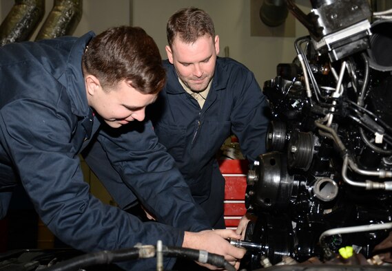 U.S. Air Force Senior Airman Samuel Lehmann, left, and U.S. Air Force Senior Airman Joshua Floyd, both 100th Logistics Readiness Squadron vehicle maintenance journeymen, install an engine on a government vehicle Nov. 24, 2015, on RAF Mildenhall, England. The vehicle is assigned to the 100th Maintenance Squadron Aerospace Ground Equipment section for movement of vital aircraft servicing equipment. (U.S. Air Force photo by Gina Randall/Released)