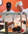 U.S. Air Force Col. Michael Pyburn, the 509th Operations Group commander, carves a ham for customers with Airman Mandel Elam Jr., a food service specialist with the 509th Force Support Squadron, during a Thanksgiving luncheon at Whiteman Air Force Base, Mo., Nov. 26, 2015. During the luncheon, customers were treated to traditional Thanksgiving foods, to include roasted turkey, baked ham, mashed potatoes, vegetable sides and an array of desserts. (U.S. Air Force photo by Airman 1st Class Jazmin Smith)