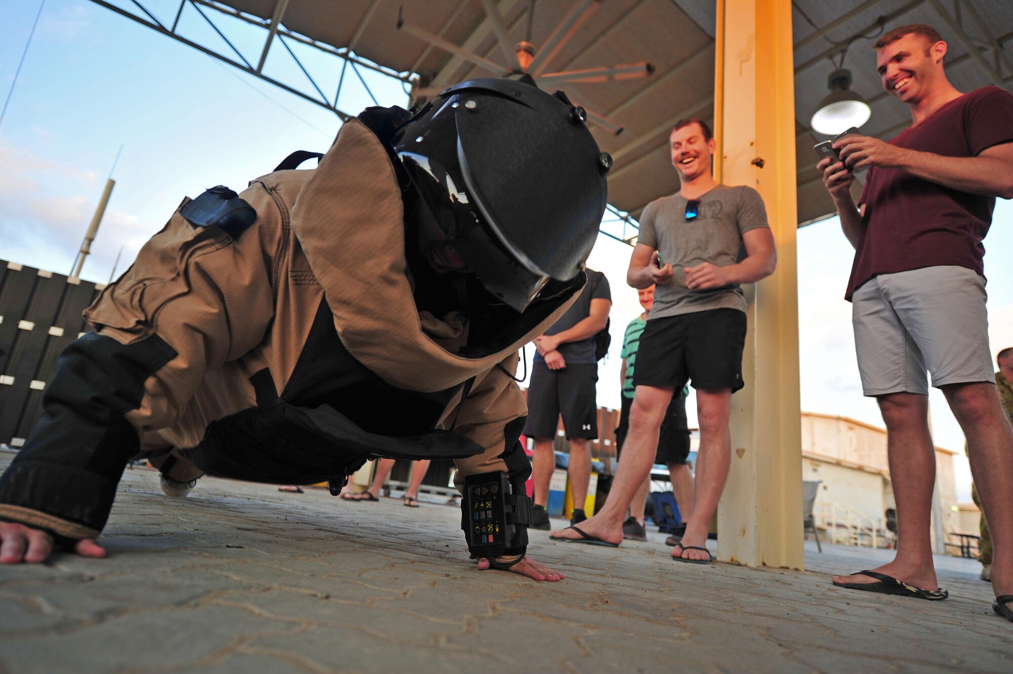 A Royal Australian Air Force airman attempts to do a pushup as part of the Bomb Suit Pushup Challenge during the Explosive Ordnance Disposal Capabilities Carnival at an undisclosed location in Southwest Asia, Nov. 27, 2015. Contenders came forward to take on the challenge, donning approximately 80 pounds of gear before attempting the most pushups they could muster in one-minute. (U.S. Air Force photo by Staff Sgt. Kentavist P. Brackin/Released)