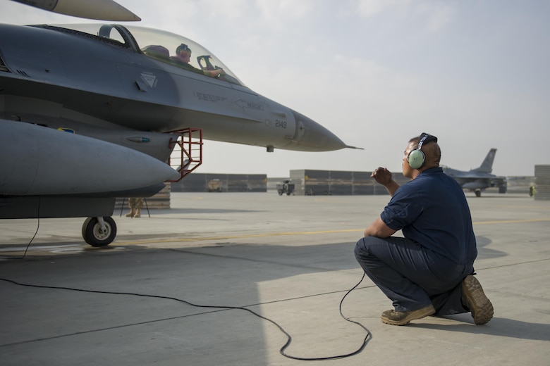 Tech. Sgt. Carlo Patalinghug, 455th Expeditionary Aircraft Maintenance Squadron crew chief, deployed Hill Air Force Base, Utah, talks with teammate via headset during a hydraulic leak repair at Bagram Airfield, Afghanistan, Nov. 30, 2015.  The squadron provides combat-ready aircraft to the air component commander in support of coalition forces throughout Afghanistan. (U.S. Air Force Photo by Tech. Sgt. Robert Cloys/Released)