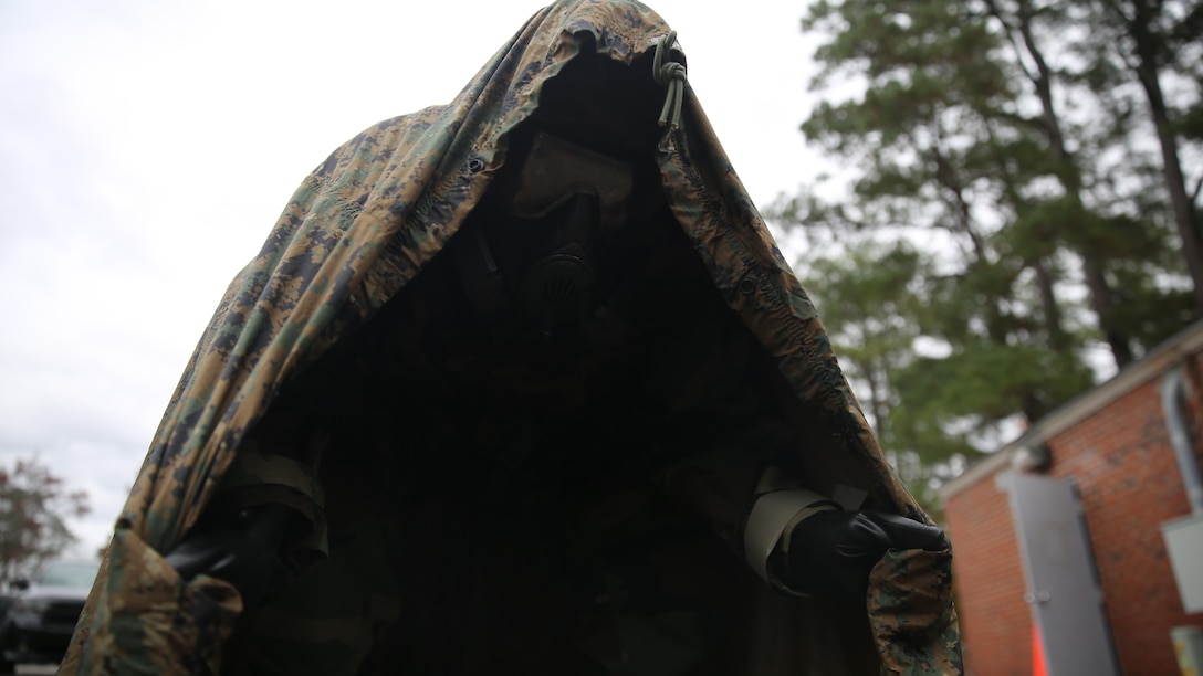 A Marine with 2nd Transport Support Battalion crouches in the chemical spray safety position with his back and tarp against the wind during chemical, biological, radioactive and nuclear defense training held at Camp Lejeune, N.C., Dec. 1, 2015. Marines applied information obtained in classes about an active chemical threat and the proper protective equipment to decontaminate themselves in a CBRN situation.