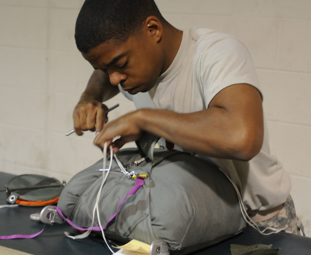 U.S. Army Spc. Frederick Gardner, with 824th Quartermaster Company, works on attaching a ripcord assembly to a T11 reserve parachute that will be used in Operation Toy Drop. He has been a part of the unit for four years. (U.S. Army photo by Staff Sgt. Shaiyla Hakeem)