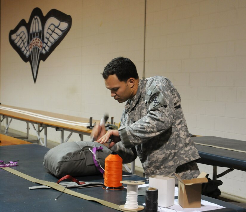 U.S. Army Spc. Christopher Locklear, with 824th Quartermaster Company, folds a T11 reserve parachute that will be used in Operation Toy Drop. (U.S. Army photo by Staff Sgt. Shaiyla Hakeem)
