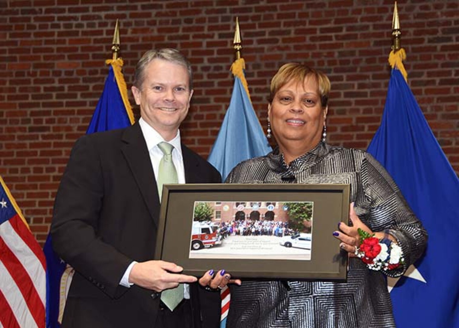 David Gibson, site director, DLA Installation Support at Richmond, Virginia, presents Lucy Lewis, president of the American Federation of Government Employees Local 1992, with a commemorative photo of installation support employees during a ceremony Nov. 24, 2015 in the Frank B. Lotts Conference Center on the occasion of her retirement from federal service after 41 years.