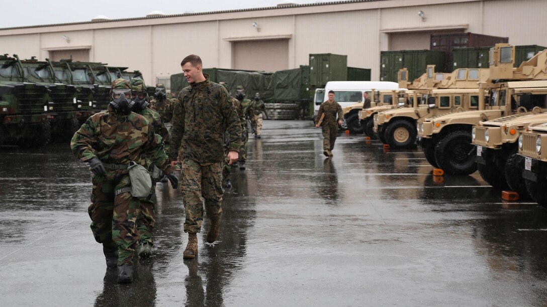 Lance Cpl. William Hony, center, chemical, biological, radiological and nuclear chief with Marine Wing Support Squadron 171, leads reconnaissance, surveillance and decontamination Marines to the contaminated area during a simulated chemical attack at the MWSS-171 motor transportation wash rack at Marine Corps Air Station Iwakuni, Japan, Nov. 18, 2015. As part of an operational decontamination exercise, the RSD team decontaminated vehicles, and performed a MOPP exchange to thoroughly review each other’s PPE and ensure Marines could safely resume normal operations.