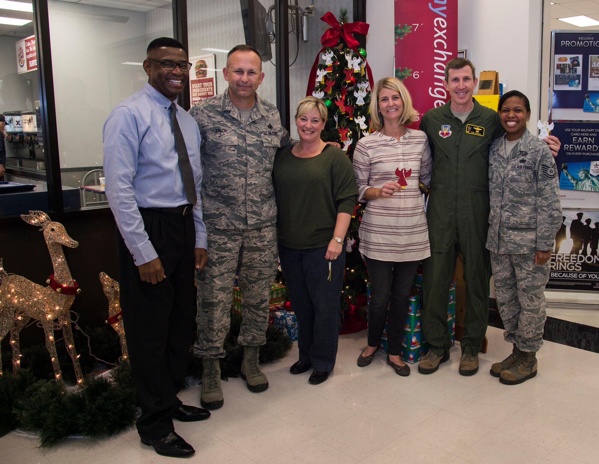 The leadership of the 23d Wing, their spouses and members of the Airman and Family Readiness Center pose in front of the Angel Tree after choosing ornaments with names, Nov. 30, 2015, at Moody Air Force Base, Ga. Moody members have until Dec. 14 to choose a name and donate gifts to children this year. (U.S. Air Force photo by Staff Sgt. Eric Summers Jr./Released)
