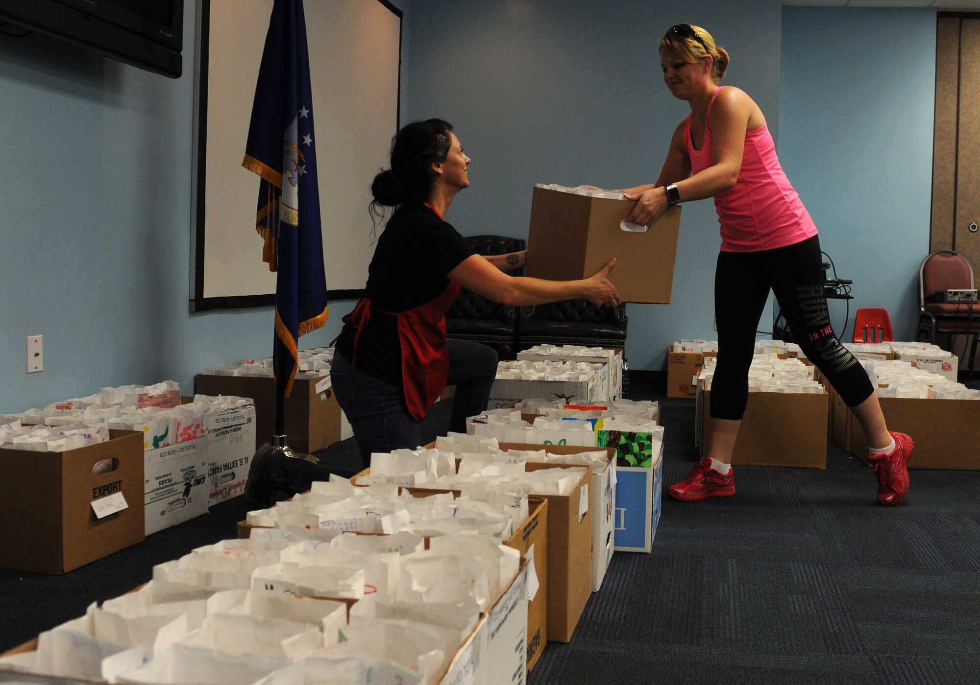Felicha Janoski, right, wife of U.S. Air Force Col. Michael Schultz, 476th Fighter Group, hands a box of cookies to Rachel Sumja, cookie drive event coordinator, during the Annual Airmen’s Cookie Drive, Dec. 1, 2015, at Moody Air Force Base, Ga. The Child Development Center, Youth Center and local schools decorated the bags for the Airmen living in the dorms on base. (U.S. Air Force photo by Airman 1st Class Kathleen D. Bryant/Released)
