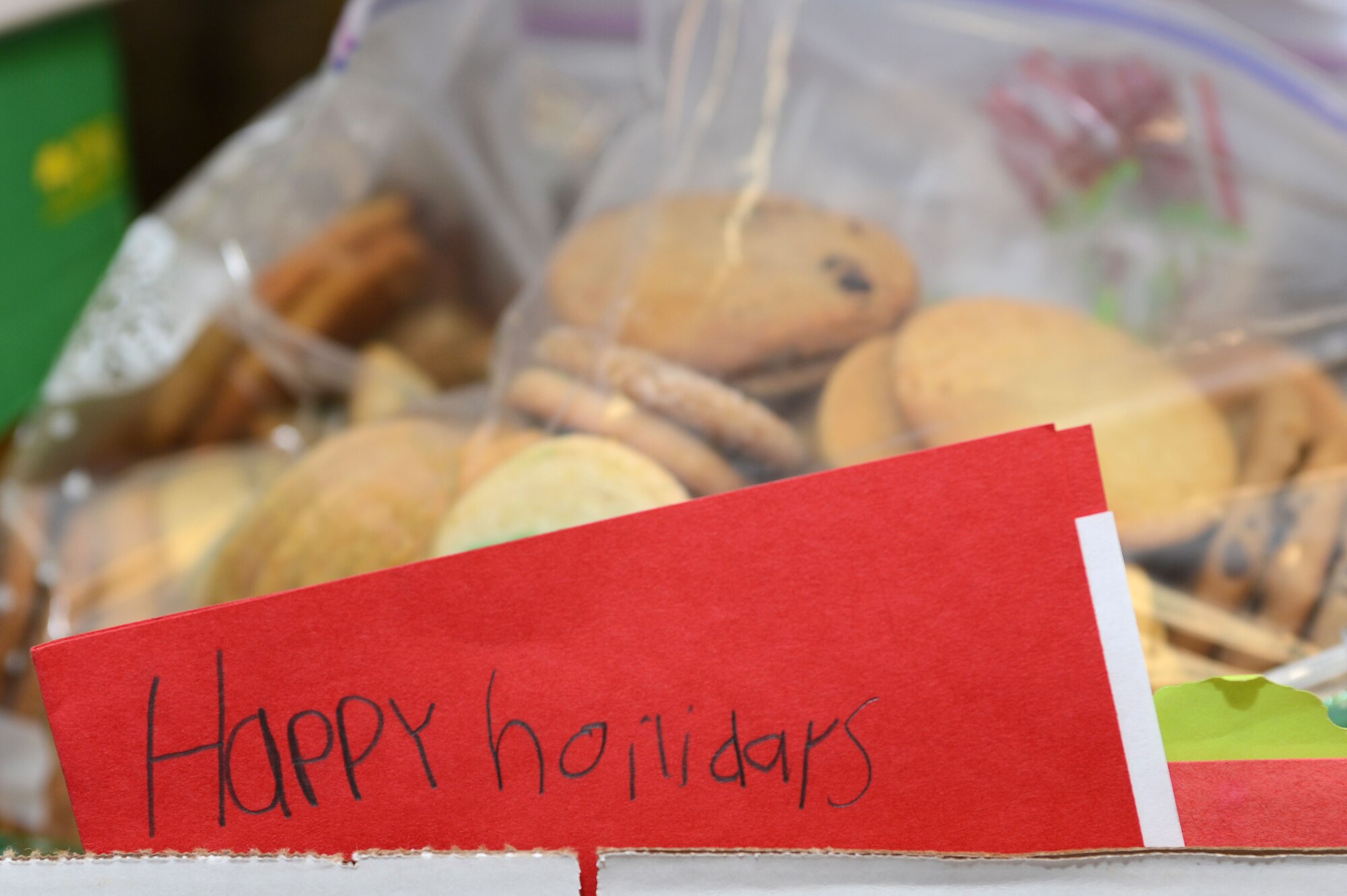 A hand-made holiday card from a local elementary school student sits with bags of cookies baked by volunteers at the Team Shaw Officers’ Spouses Club’s annual holiday cookie drive at Shaw Air Force Base, S.C., Dec. 3, 2015. More than 43,000 home-made treats and 5,000 cards were collected by the OSC from schools, churches, small businesses and other organizations in the Shaw community to be distributed to Team Shaw’s dormitory residents and deployed personnel. (U.S. Air Force photo by Senior Airman Zade Vadnais)