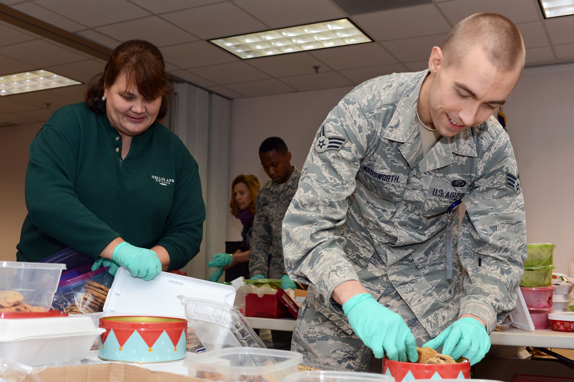 Patty Bessmer, a Team Shaw Officers’ Spouses Club member, and Senior Airman Justin Wadsworth, 20th Medical Group command support staff technician, pack holiday treats into individual bags during the OSC's annual holiday cookie drive at Shaw Air Force Base, S.C., Dec. 3, 2015. Each year, the holiday cookie drive collects thousands of home-made treats and hand-written cards from various organizations in the Shaw community, separates them into individual portions, and has them delivered to Team Shaw’s deployed personnel as well as those living in the dormitories on base. (U.S. Air Force photo by Senior Airman Zade Vadnais)