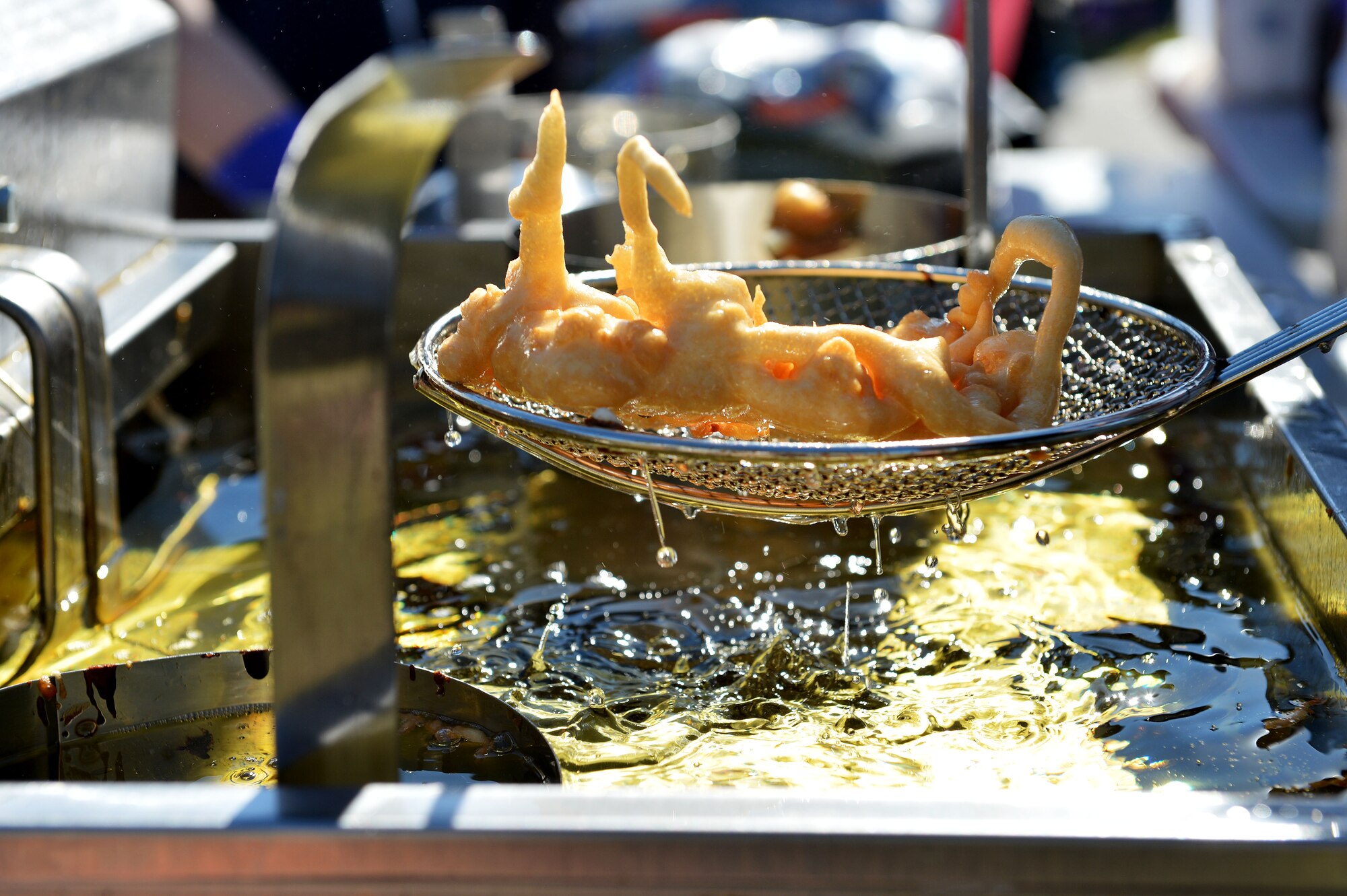 An Airman pulls a funnel cake from a deep fryer during a Fall Family Picnic event at Shaw Air Force Base, S.C., Nov. 21, 2015. The 20th Fighter Wing volunteers provided free food, games, and inflatables for Team Shaw members. (U.S. Air Force photo by Senior Airman Diana M. Cossaboom)