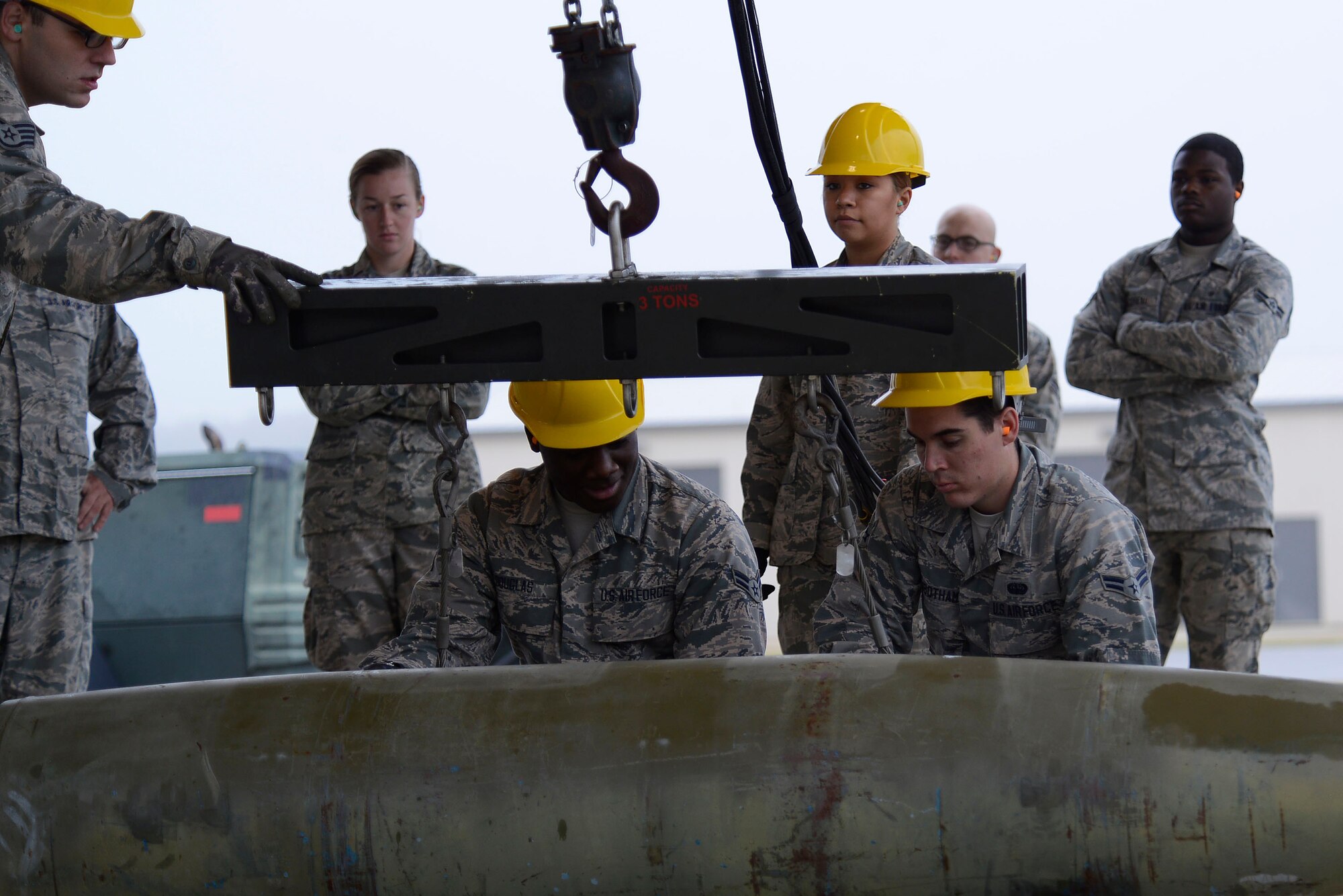 Team Shaw Airmen prepare to lift an inert munition during an Ammo assembly demonstration at Shaw Air Force Base, S.C., Dec. 1, 2015. The demonstration gave 20th Equipment Maintenance Squadron munition flight Airmen the opportunity to teach non-munitions Airmen how to assemble the munitions that are loaded onto the F-16CM Fighting Falcon. (U.S. Air Force photo by Airman 1st Class Christopher Maldonado)