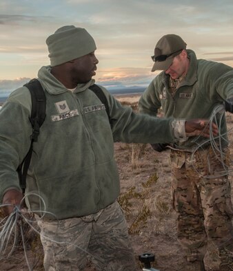 Tech Sgt. Cornelius Pace and Staff Sgt. Curtis Bonham, Hammer Adaptive Communication Element operatives, roll up communication wires outside an F-16 crash site northwest of Salinas Peak, New Mexico on Nov. 26. Hammer A.C.E. teams consist of three members, each with a specific expertise in communications. (U.S. Air Force photo by Airman 1st Class Randahl J. Jenson) 
