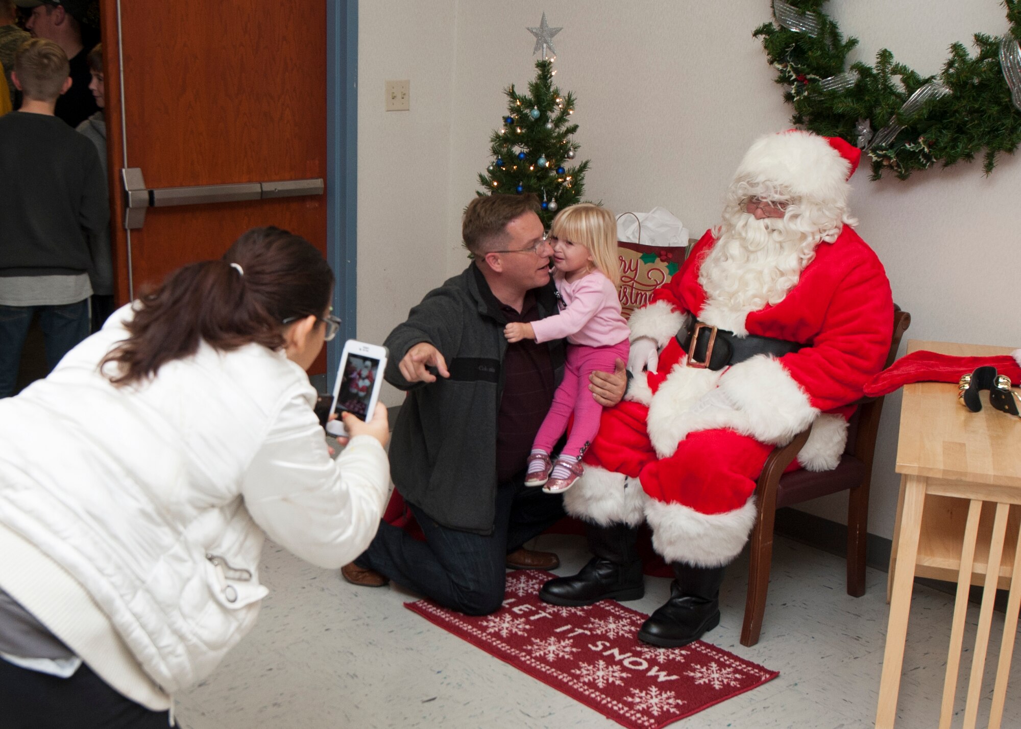 Candy Lauffer takes a picture of her husband Master Sgt. James Lauffer, 436th Logistics Readiness Squadron fleet management and analyst superintendent, and their daughter Makayla Lauffer, 2, with Santa Claus during the 2015 Dover Air Force Base Holiday Tree Lighting ceremony Dec. 1, 2015, at Chapel 2 on Dover AFB, Del. Santa posed for photos and met with the children who attended the event. (U.S. Air Force photo/Senior Airman Zachary Cacicia)